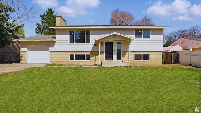 raised ranch featuring concrete driveway, french doors, a front lawn, a garage, and fence