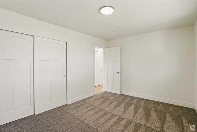 unfurnished bedroom featuring a closet, baseboards, a textured ceiling, and carpet floors