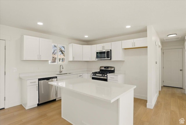 kitchen with stainless steel appliances, white cabinetry, a sink, and a kitchen island