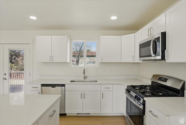 kitchen with a healthy amount of sunlight, a sink, white cabinetry, and stainless steel appliances
