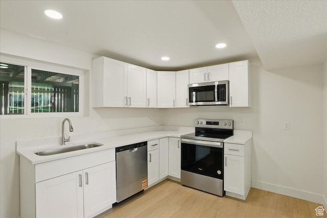 kitchen featuring light countertops, white cabinetry, light wood-style floors, stainless steel appliances, and a sink