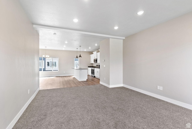 632 E 730 N, Hyrum, UT 84319 - unfurnished living room with a notable chandelier, a sink, baseboards, and carpet floors