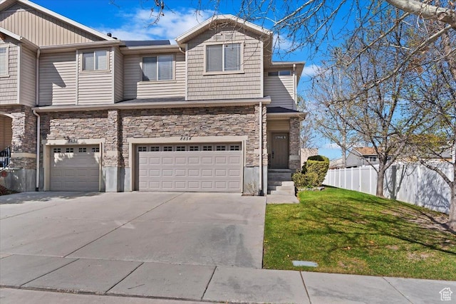 view of front of home with a garage, a front yard, stone siding, fence, and driveway