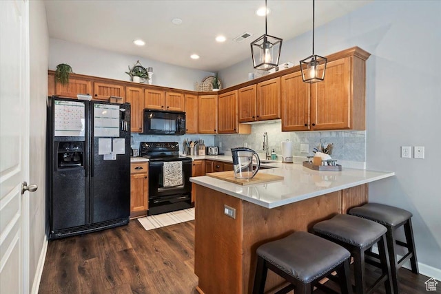kitchen with brown cabinetry, a peninsula, visible vents, black appliances, and dark wood-style flooring