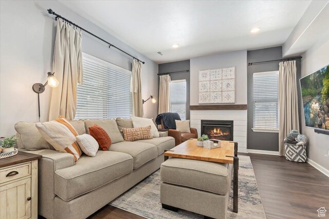 living room featuring a glass covered fireplace, plenty of natural light, dark wood-style floors, and baseboards