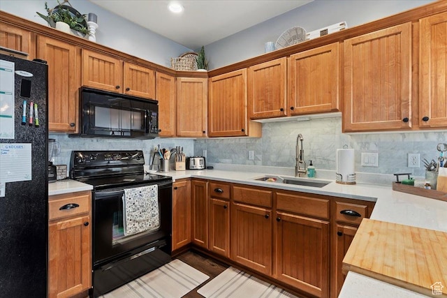 kitchen with brown cabinets, a sink, backsplash, and black appliances