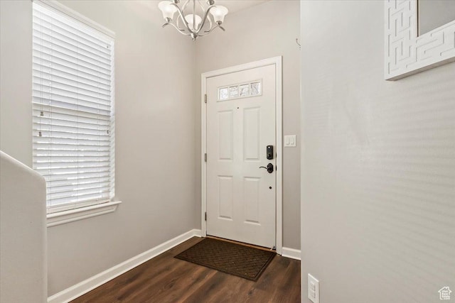 entrance foyer featuring a chandelier, dark wood-type flooring, and baseboards