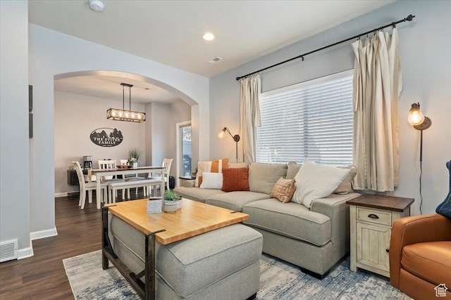 living area with dark wood finished floors, arched walkways, visible vents, recessed lighting, and baseboards