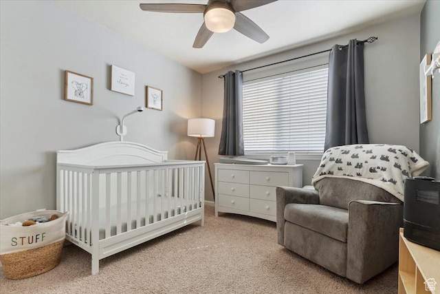 bedroom featuring a crib, a ceiling fan, and carpet floors