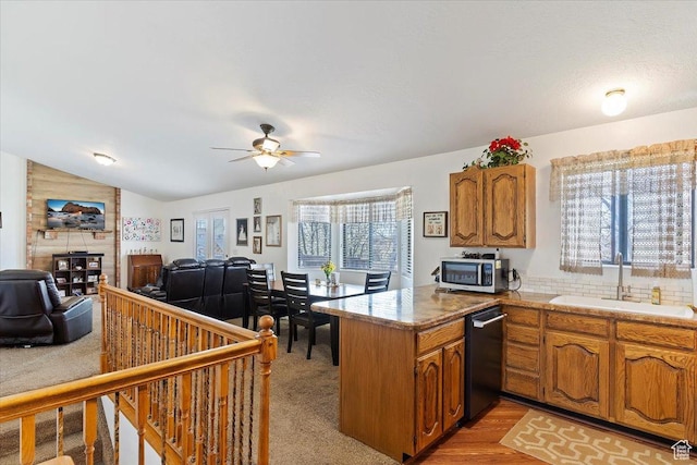 kitchen featuring brown cabinetry, a peninsula, a ceiling fan, a sink, and stainless steel appliances