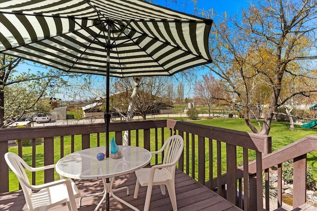 wooden deck with a yard and outdoor dining area