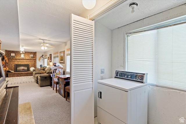laundry area featuring laundry area, a fireplace, washer / clothes dryer, a textured ceiling, and a ceiling fan