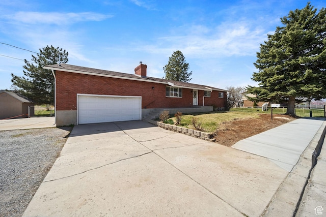 single story home with brick siding, a chimney, a garage, and concrete driveway