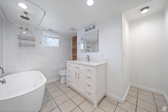 full bath with a freestanding tub, vanity, toilet, tile walls, and tile patterned floors