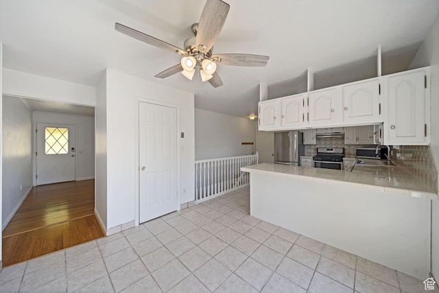 kitchen featuring a ceiling fan, white cabinets, stainless steel appliances, tile countertops, and a sink