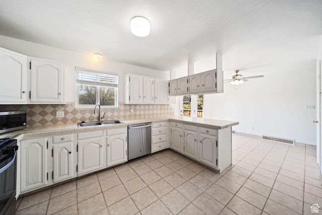 kitchen with a peninsula, backsplash, visible vents, stainless steel appliances, and a sink