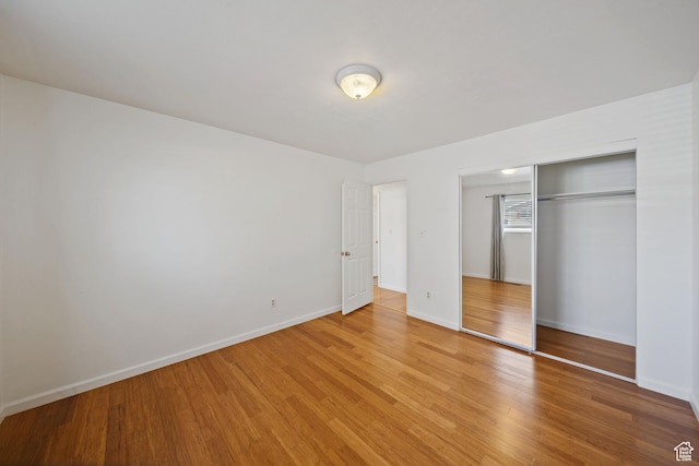 unfurnished bedroom featuring a closet, light wood-style flooring, and baseboards