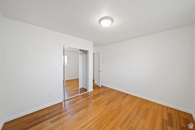 unfurnished bedroom with a closet, light wood-type flooring, and baseboards