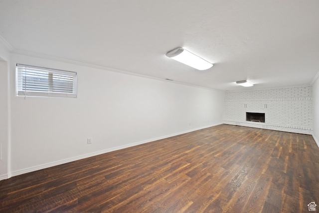 below grade area featuring dark wood-type flooring, baseboards, crown molding, and a fireplace