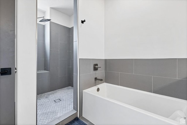 full bathroom with a tile shower and a bath