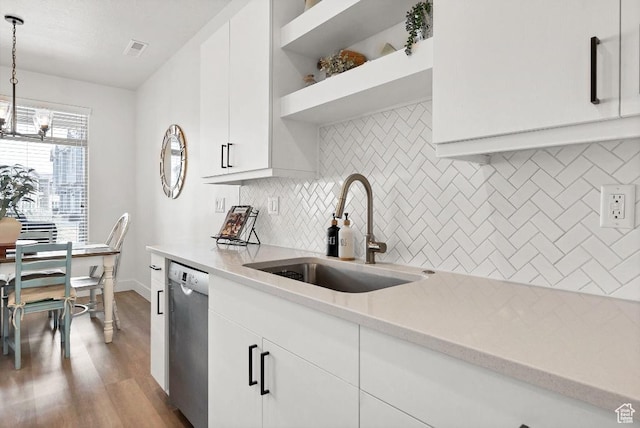 kitchen with stainless steel dishwasher, tasteful backsplash, white cabinetry, wood finished floors, and a sink