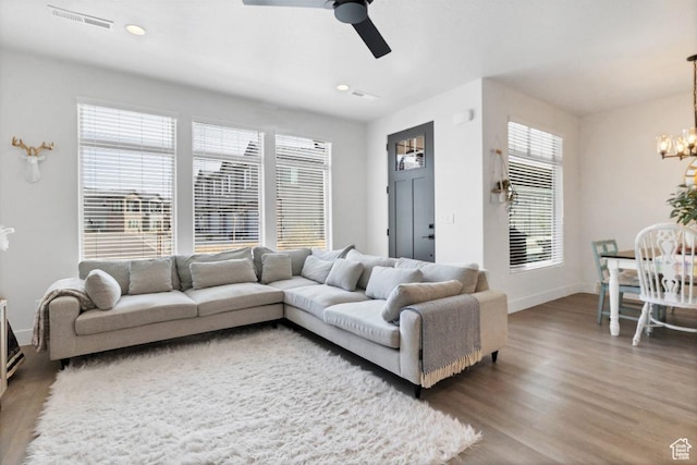 living room featuring visible vents, baseboards, recessed lighting, wood finished floors, and ceiling fan with notable chandelier