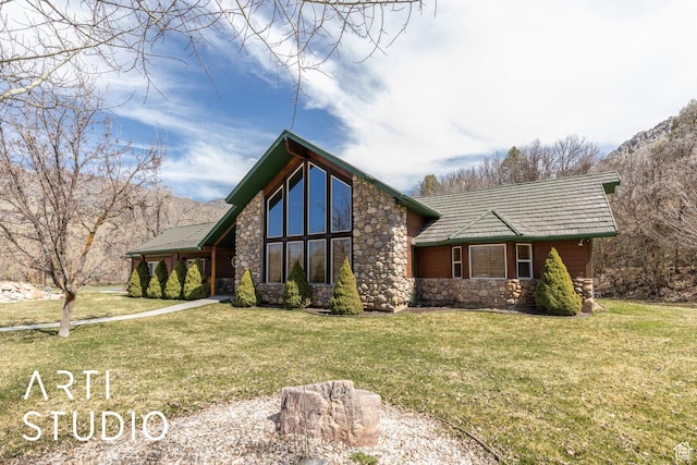 view of front facade featuring stone siding, a mountain view, and a front lawn