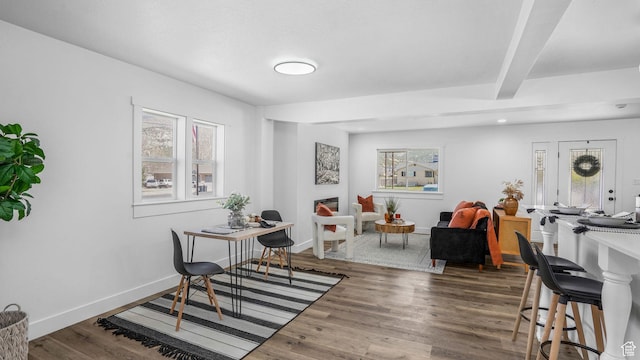 dining area featuring beamed ceiling, baseboards, and wood finished floors