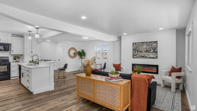 living room featuring baseboards, recessed lighting, a glass covered fireplace, and wood finished floors