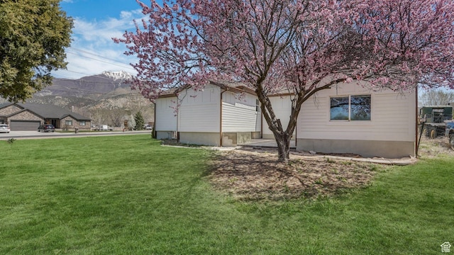 view of side of home with a mountain view and a lawn