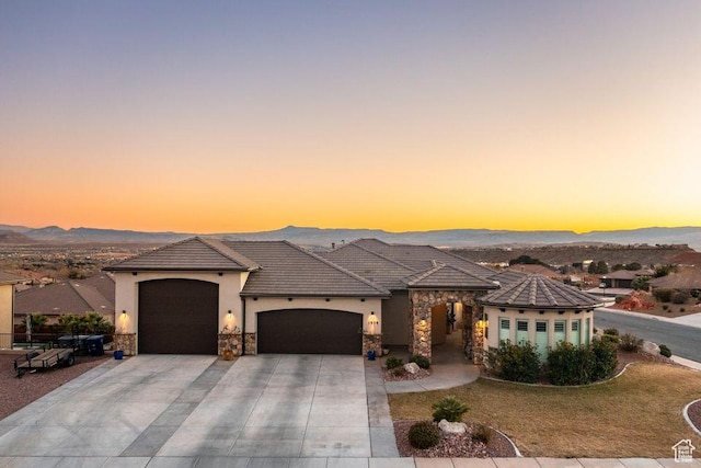 view of front of house featuring concrete driveway, stucco siding, stone siding, a tile roof, and a garage