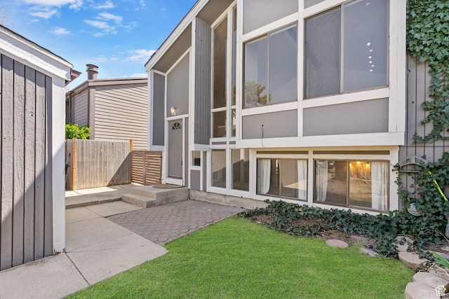 property entrance featuring fence, a patio, and a yard