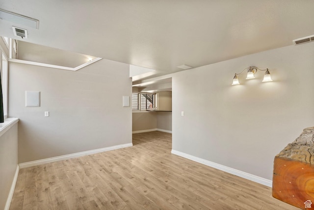 unfurnished room with baseboards, wood finished floors, and visible vents
