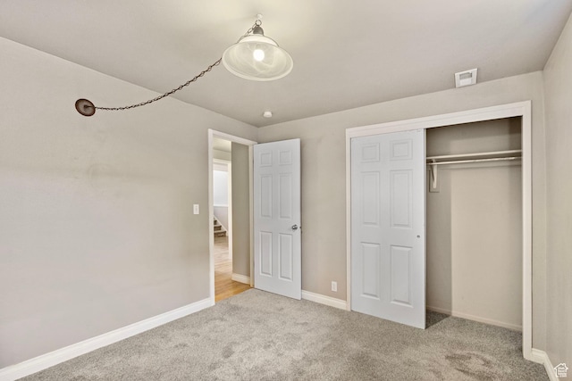 unfurnished bedroom featuring carpet flooring, baseboards, visible vents, and a closet