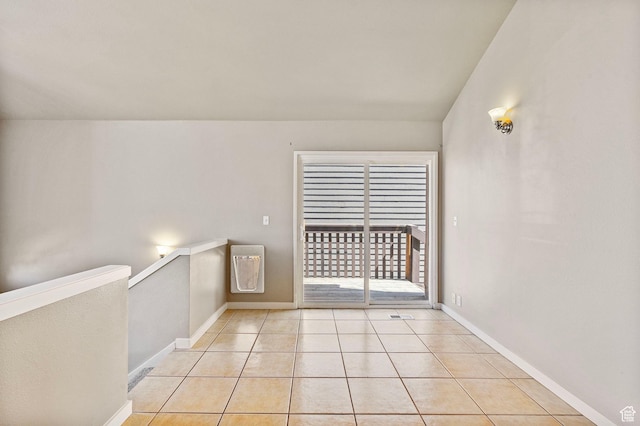 empty room featuring baseboards and light tile patterned flooring