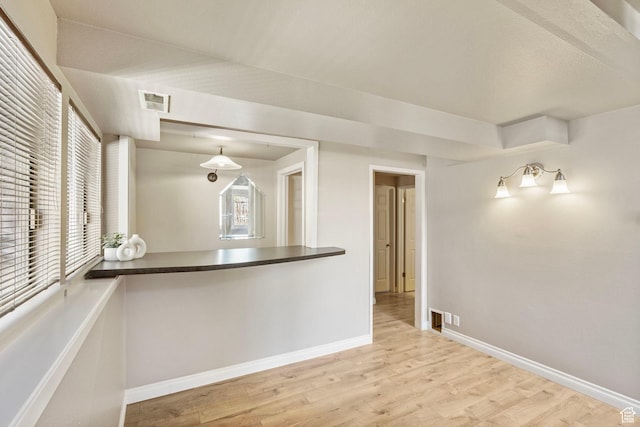 empty room featuring baseboards, wood finished floors, and visible vents