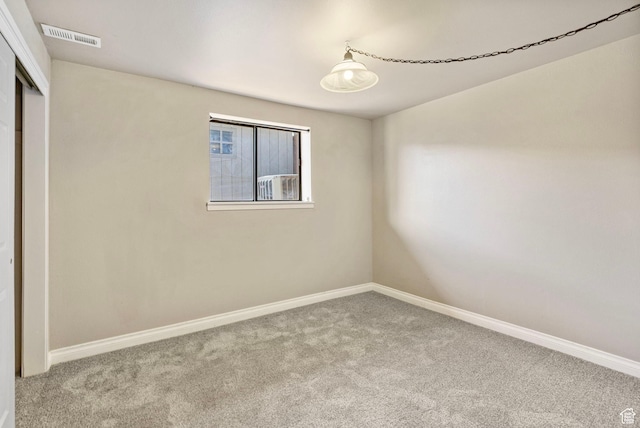 carpeted empty room featuring baseboards and visible vents