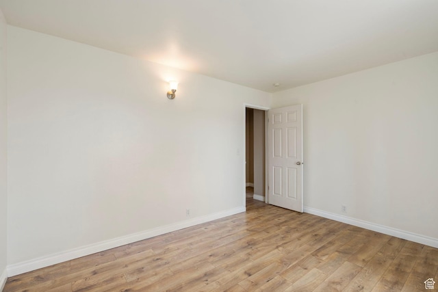 spare room with baseboards and light wood-type flooring