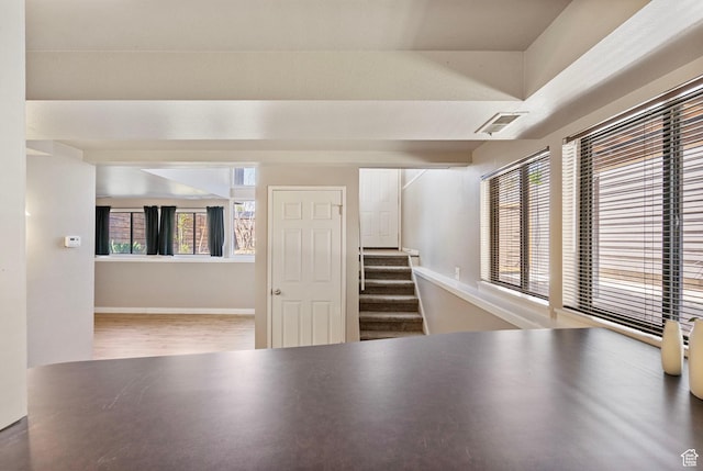 unfurnished room featuring stairs, wood finished floors, and visible vents