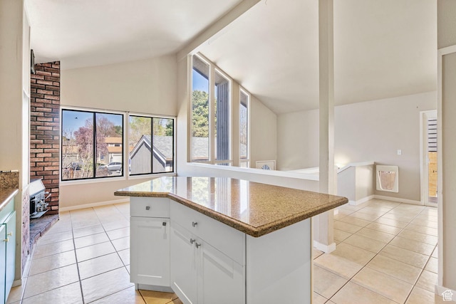 kitchen with white cabinets, vaulted ceiling, a kitchen island, and light tile patterned floors