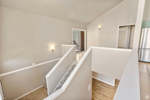 stairway featuring baseboards, wood finished floors, and lofted ceiling