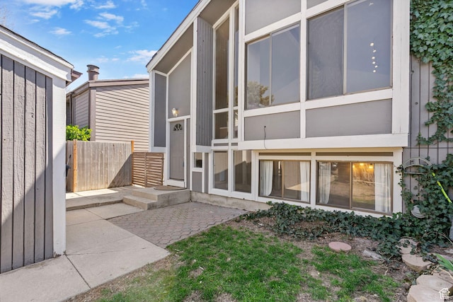 view of exterior entry with a patio and fence
