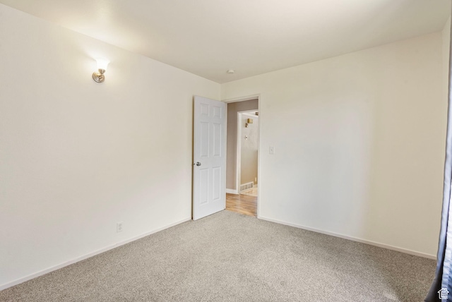 unfurnished room with baseboards, visible vents, and light carpet