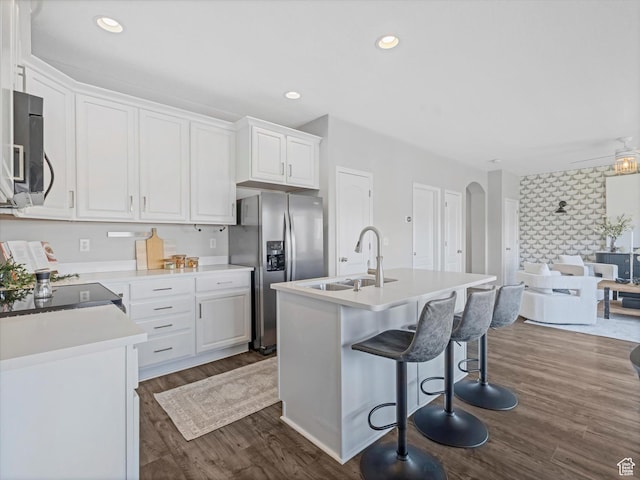 14939 S Winged Bluff Ln, Draper, UT 84020 - kitchen with stainless steel fridge, a sink, arched walkways, white cabinets, and dark wood-type flooring