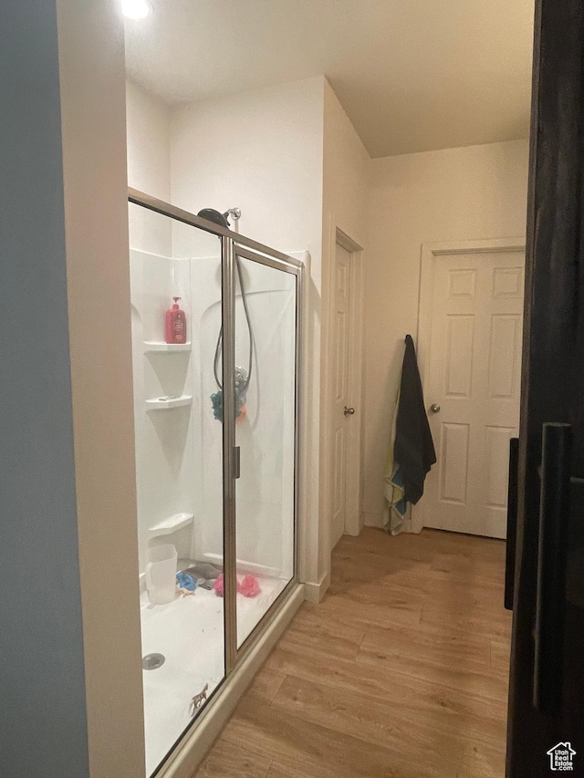 full bathroom featuring a shower stall and wood finished floors