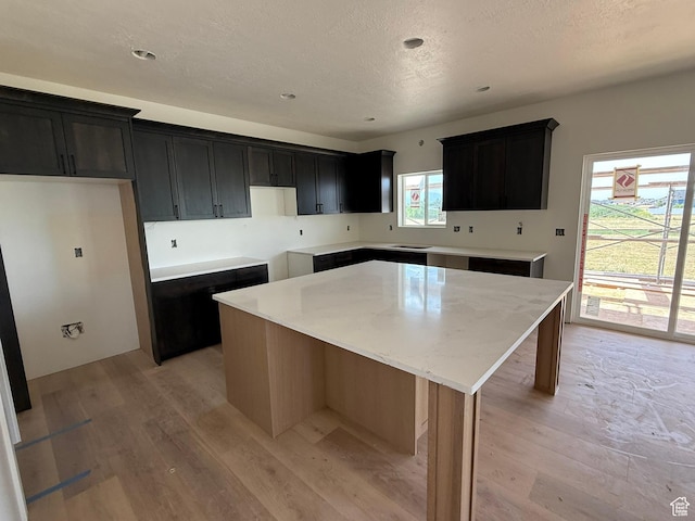 2405 W 3200 N, Farr West, UT 84404 - kitchen with a kitchen island, light wood finished floors, a textured ceiling, dark cabinets, and recessed lighting