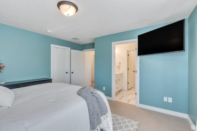 carpeted bedroom featuring a closet, baseboards, visible vents, and connected bathroom