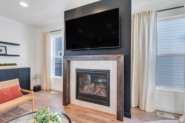 living room featuring wood finished floors, recessed lighting, visible vents, and a tile fireplace