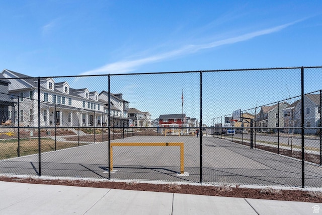 view of basketball court featuring community basketball court, a residential view, and fence