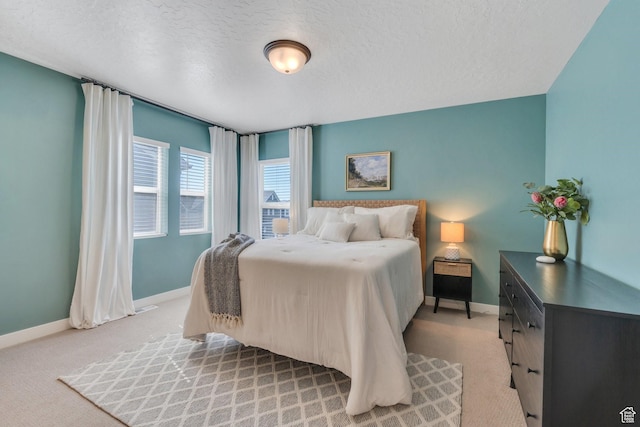 bedroom featuring baseboards, light carpet, and a textured ceiling